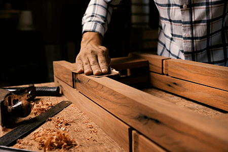 Homme ponçant un meuble en bois